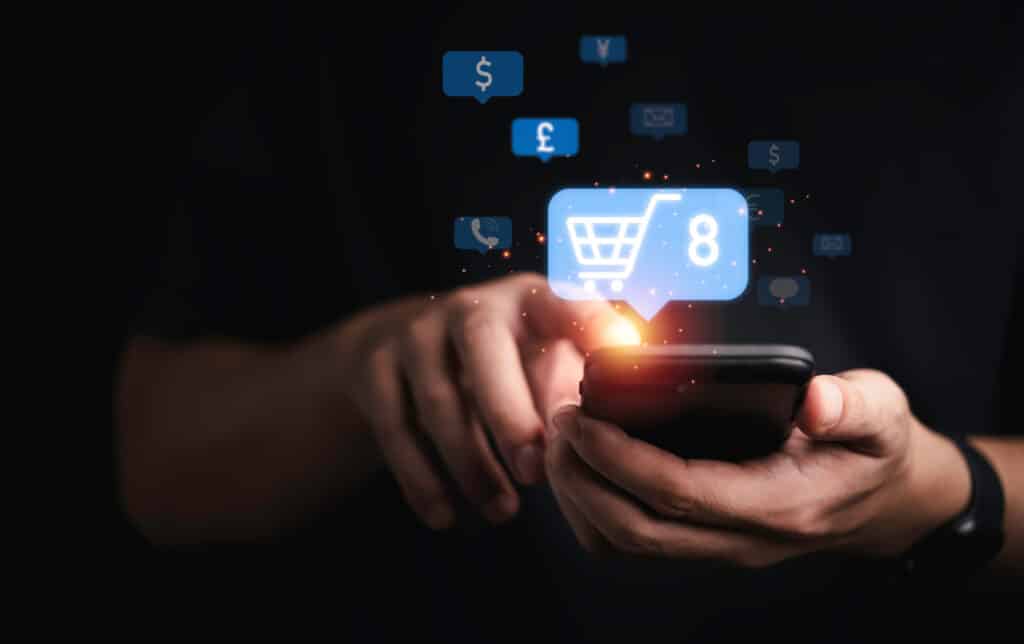 Hände die ein Smartphone halten und digital Produkte in den Warenkorb legen